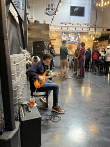 A person plays guitar while others stand around and talk