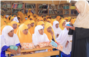 A woman speaks to a group of girls at Wilwal Primary School